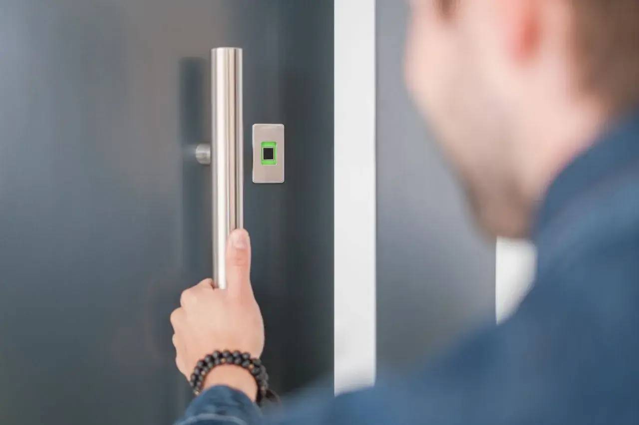 Une personne ouvre une porte équipée d'un lecteur d'empreintes digitales moderne.