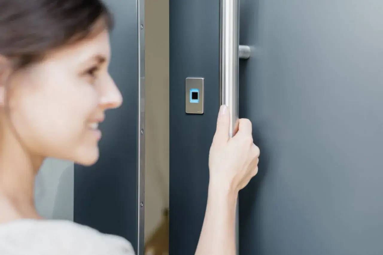 Une personne ouvre une porte métallique en utilisant un lecteur d'empreintes digitales.