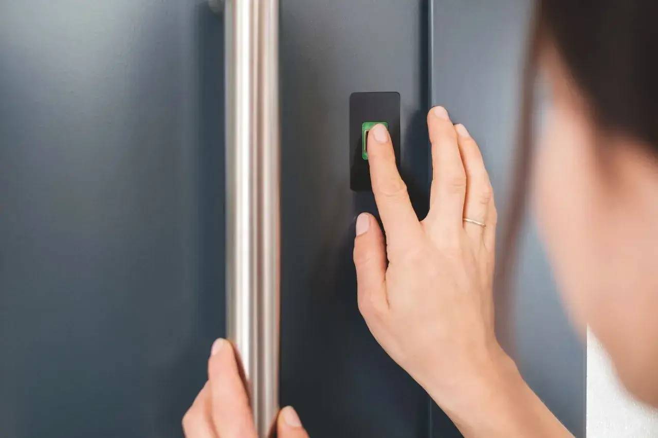 Une personne active un scanner d'empreintes digitales sur une porte.