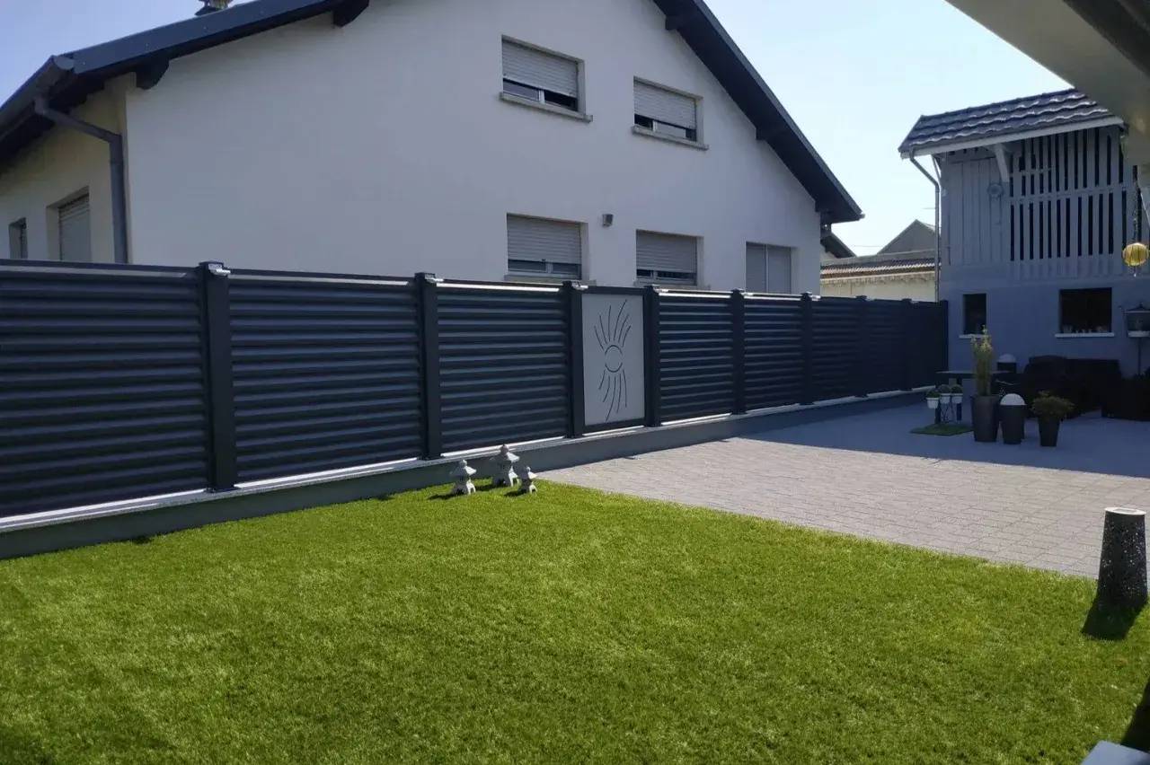 Une maison moderne avec une clôture métallique élégante et une pelouse bien entretenue.
