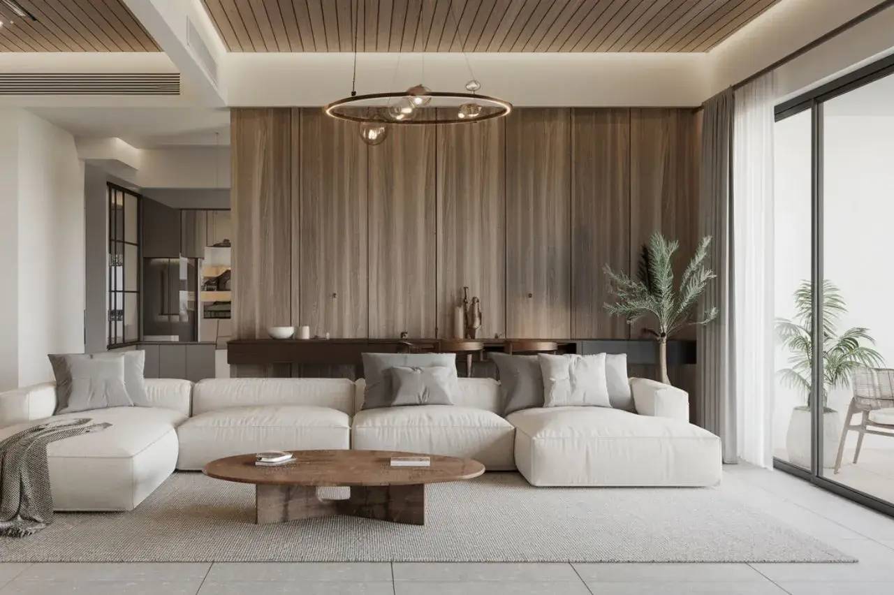 Un salon moderne et lumineux avec un grand canapé blanc, une table basse en bois, et des plantes près d'une baie vitrée.