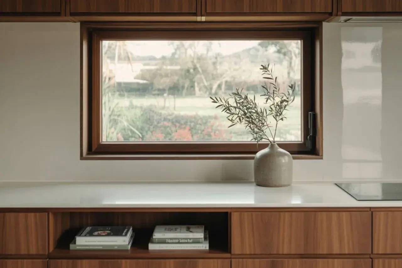 Un intérieur chaleureux avec un plan de travail en bois clair, une fenêtre donnant sur un jardin verdoyant, et un vase en céramique contenant des