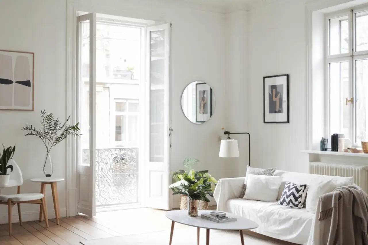 Un salon lumineux et épuré, décoré avec des meubles modernes et des touches végétales, baigné de lumière naturelle.