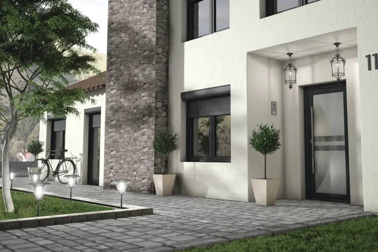 Une entrée moderne avec un mur en pierres, des lanternes suspendues, des plantes en pot, et une allée pavée équipée de luminaires