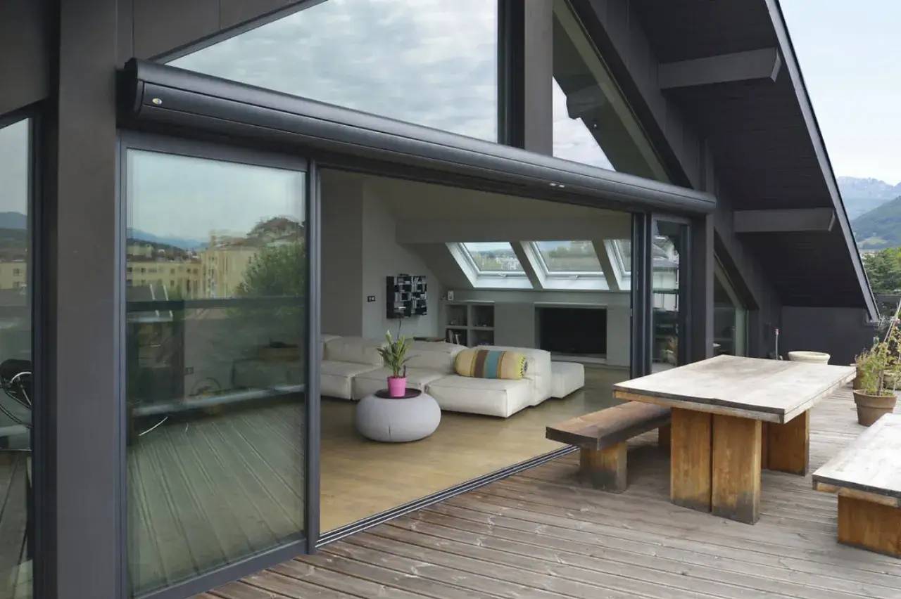 Salle de séjour moderne et lumineuse avec de grandes baies vitrées ouvrant sur une terrasse en bois.