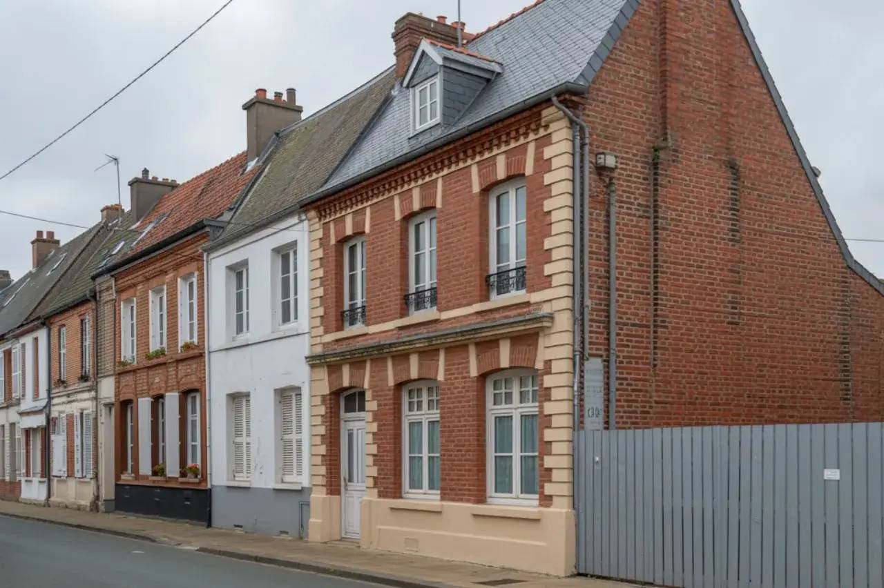 Maisons en briques rouges et blanches alignées le long d'une rue calme avec un ciel nuageux.