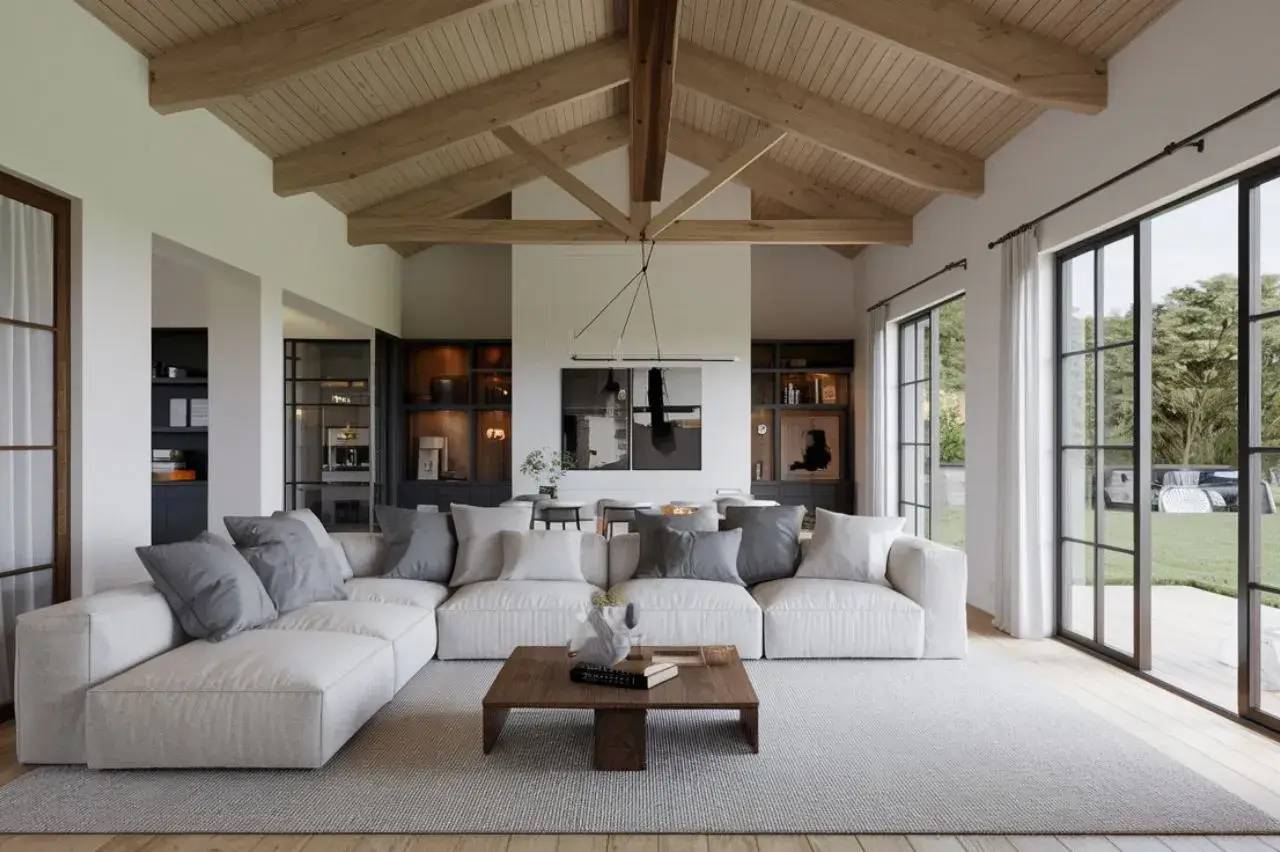 Un salon moderne et spacieux avec un grand canapé blanc, des poutres en bois apparentes et de grandes fenêtres donnant sur un jardin.