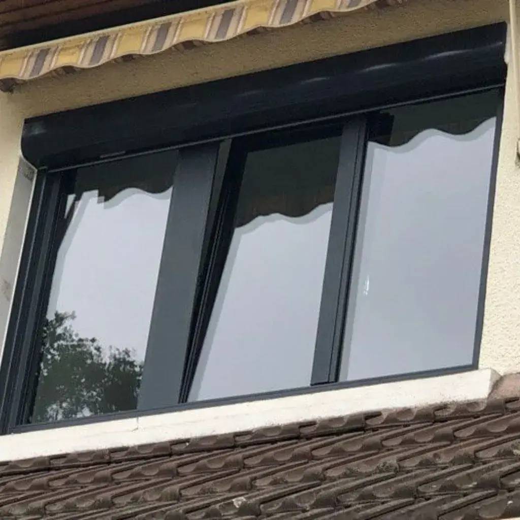 Une fenêtre moderne à double vitrage avec des cadres noirs et un auvent rayé au-dessus.