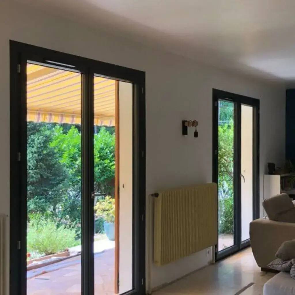 Intérieur lumineux avec de grandes portes vitrées donnant sur un jardin verdoyant.