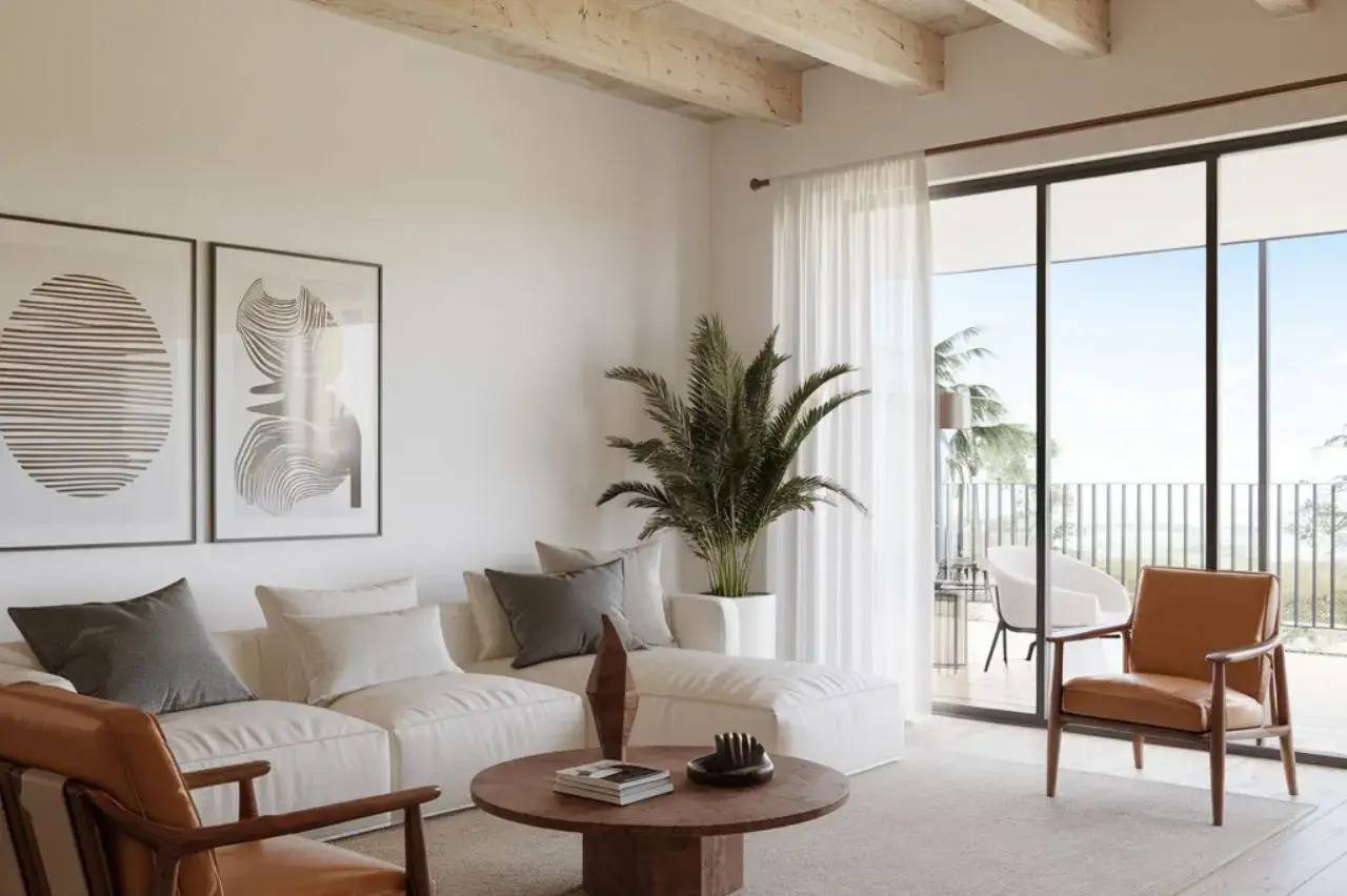 Un salon moderne et lumineux avec un canapé blanc, des œuvres d'art abstraites, une grande plante verte et des baies vitrées donnant sur un