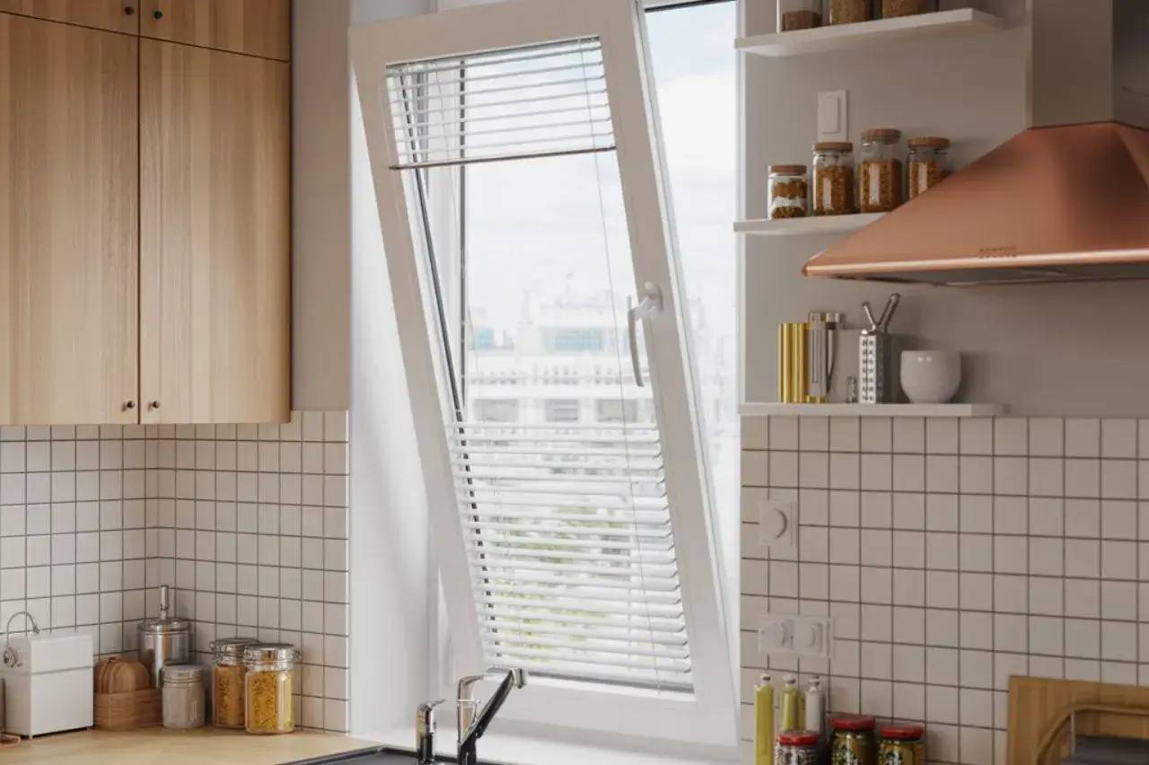 Cuisine moderne avec une fenêtre inclinée, carrelage blanc, et étagères remplies de bocaux d'épices.