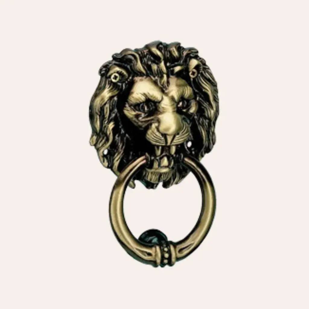 Un heurtoir de porte en forme de tête de lion dorée, avec un anneau en métal.
