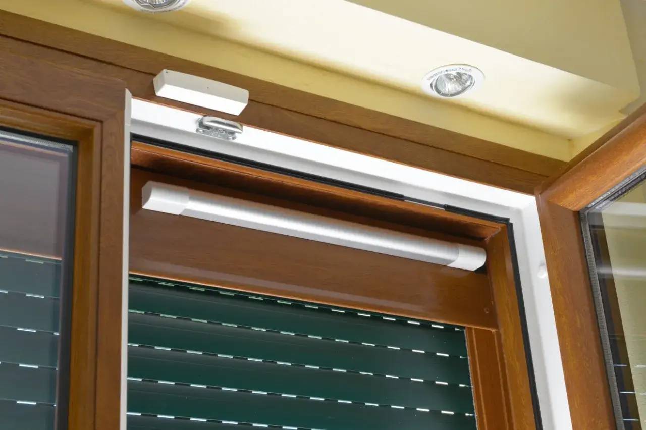 Vue en gros plan d'un volet roulant motorisé avec son mécanisme installé sur une fenêtre en bois.
