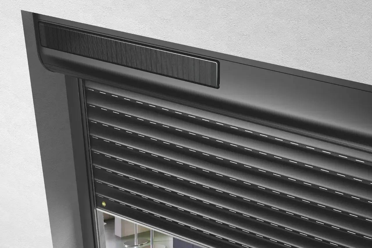 Volet roulant noir moderne fixé sur un mur clair, offrant une solution élégante pour l'obscurcissement et l'intimité des fenêtres.