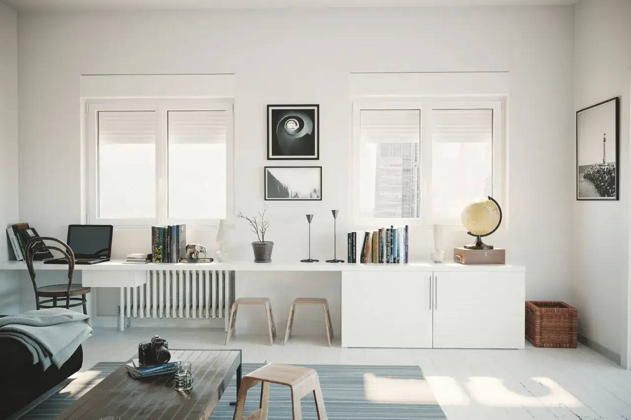 Un espace de travail lumineux et minimaliste avec des étagères blanches, des livres, un globe terrestre et une décoration murale artistique.