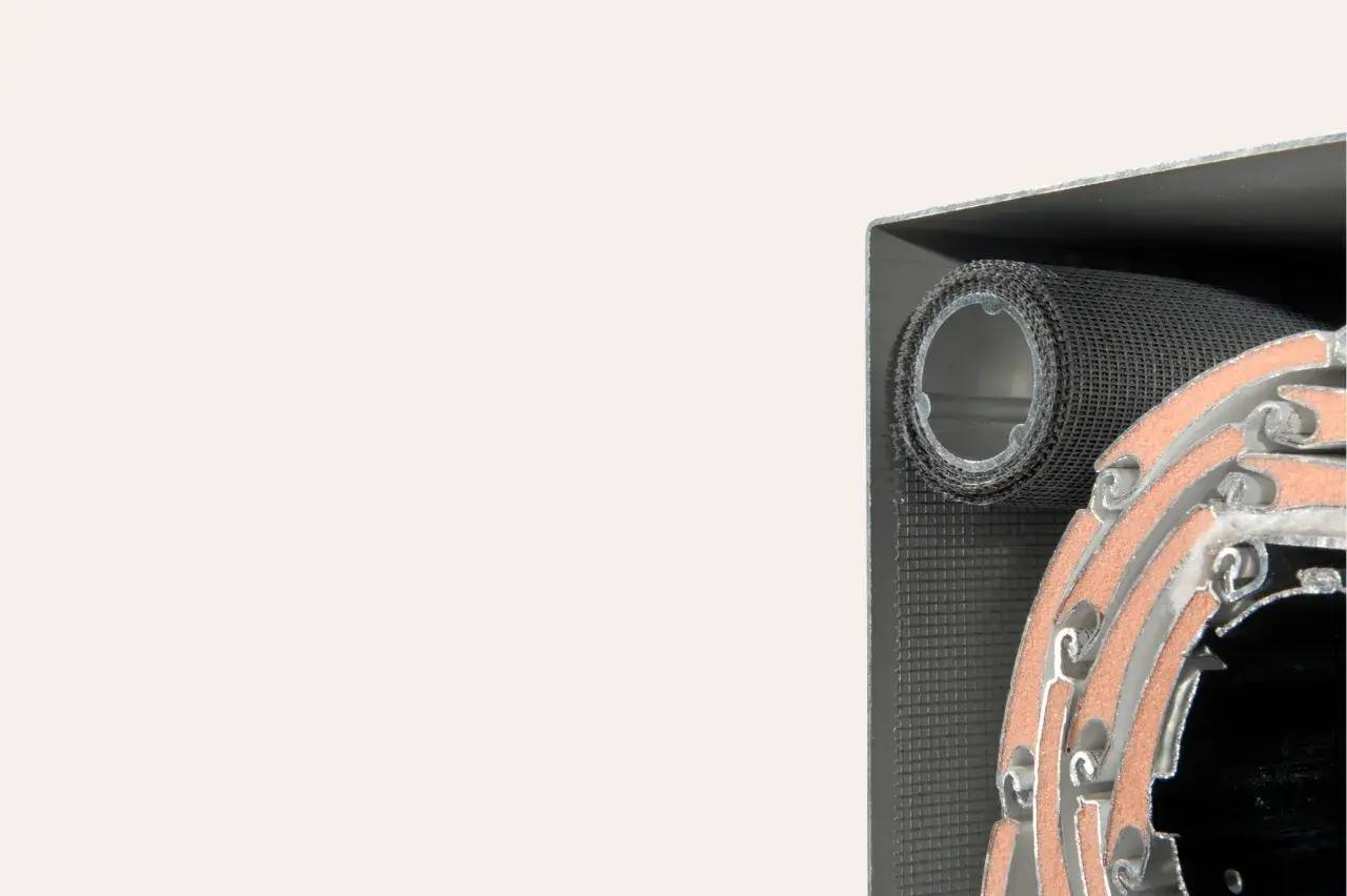 L'image montre un gros plan d'une structure métallique complexe avec des éléments circulaires et grillagés, partiellement enroulés.