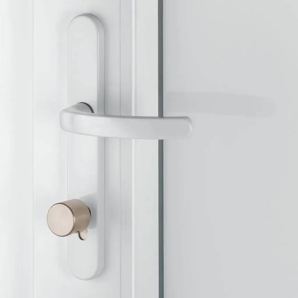 Poignée de porte moderne en métal argenté sur fond blanc, avec un dispositif de sécurité intégré.