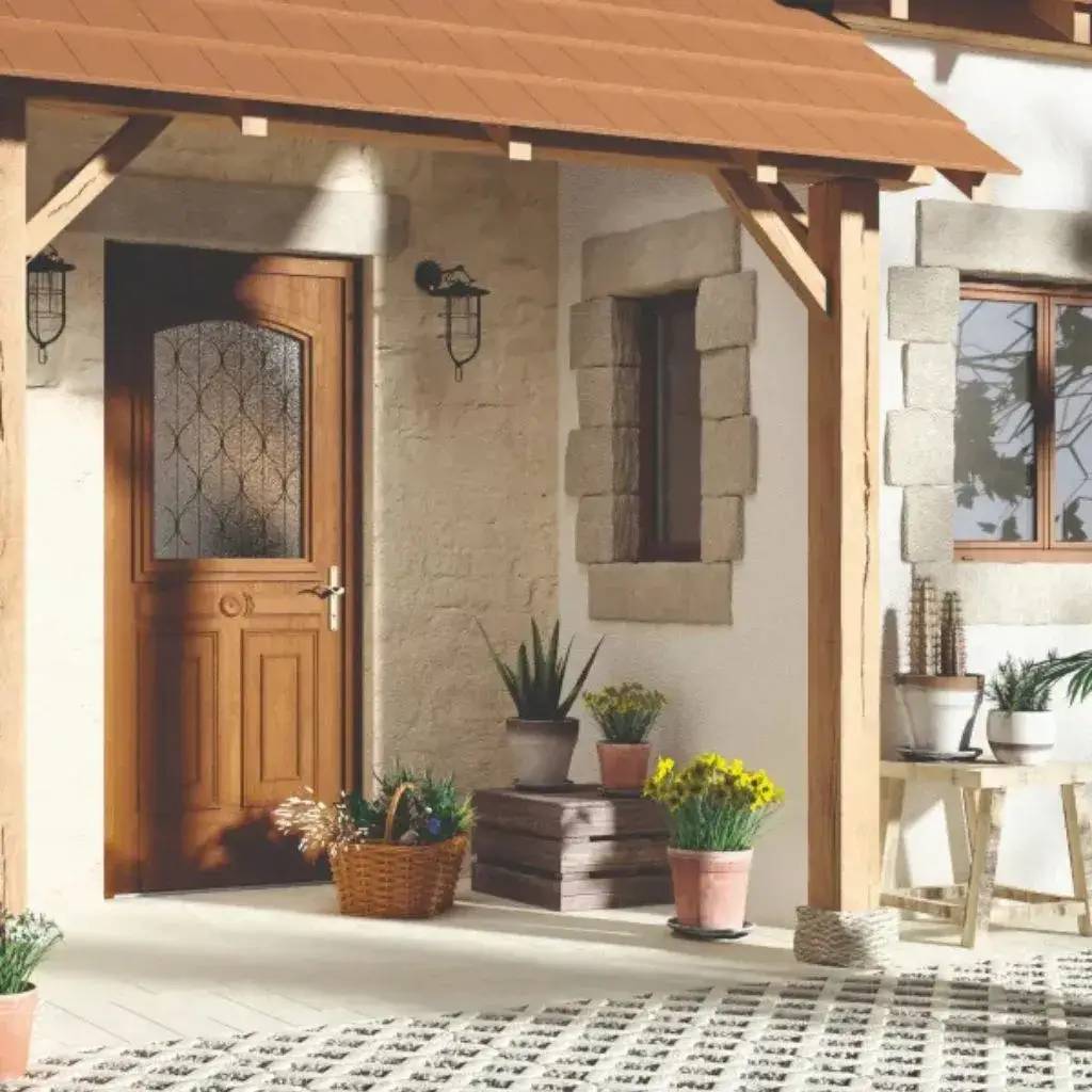 Entrée de maison accueillante avec une porte en bois, des murs en pierre et décorée de plantes en pots.