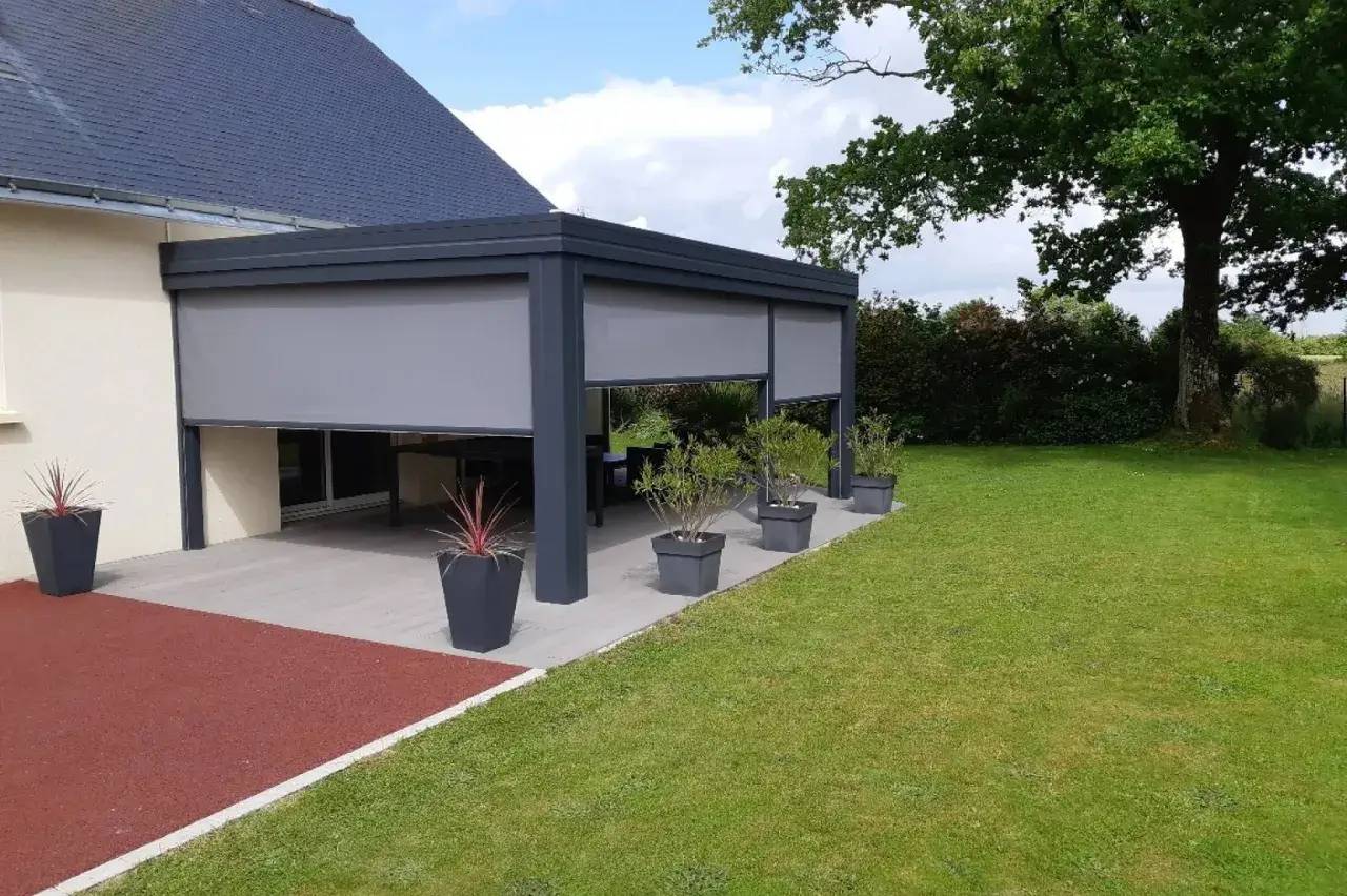 Une pergola moderne se dresse sur une terrasse, entourée de pots de plantes, devant un jardin verdoyant.