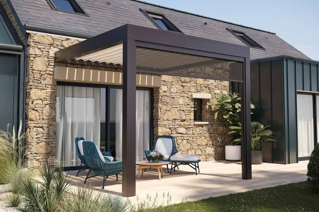 Cet espace extérieur élégant présente une pergola moderne adossée à une maison en pierre, avec un mobilier confortable et des plantes décoratives.