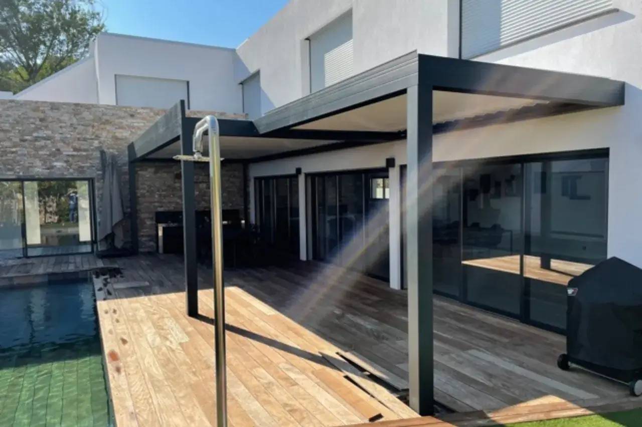 Terrasse moderne en bois avec piscine et pergola, intégrée à une maison contemporaine.