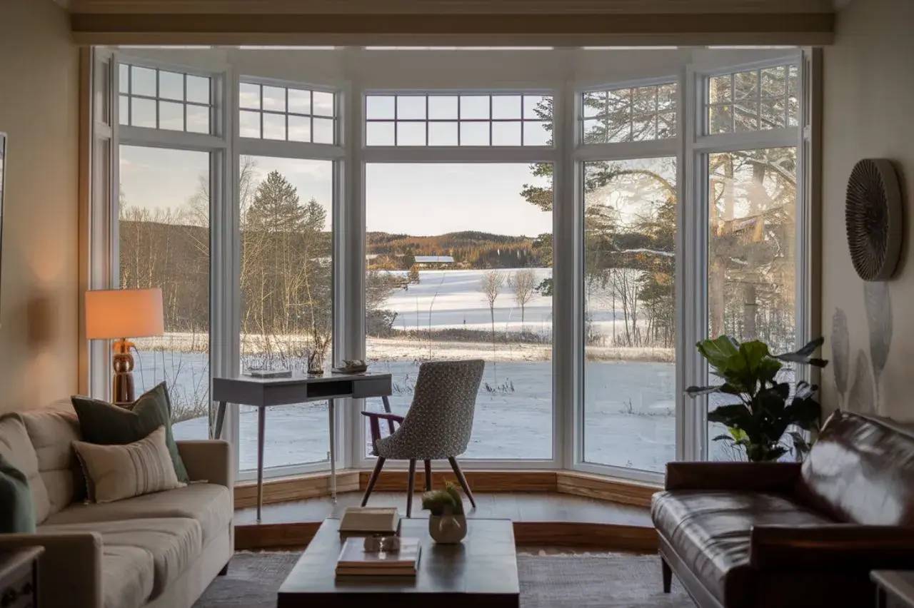 Un salon cosy avec une vue panoramique sur un paysage enneigé à travers de grandes baies vitrées.