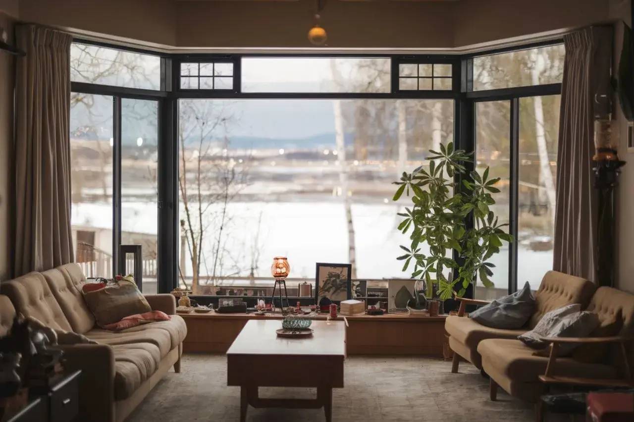 Un salon chaleureux avec de grandes fenêtres offrant une vue sur un paysage hivernal.