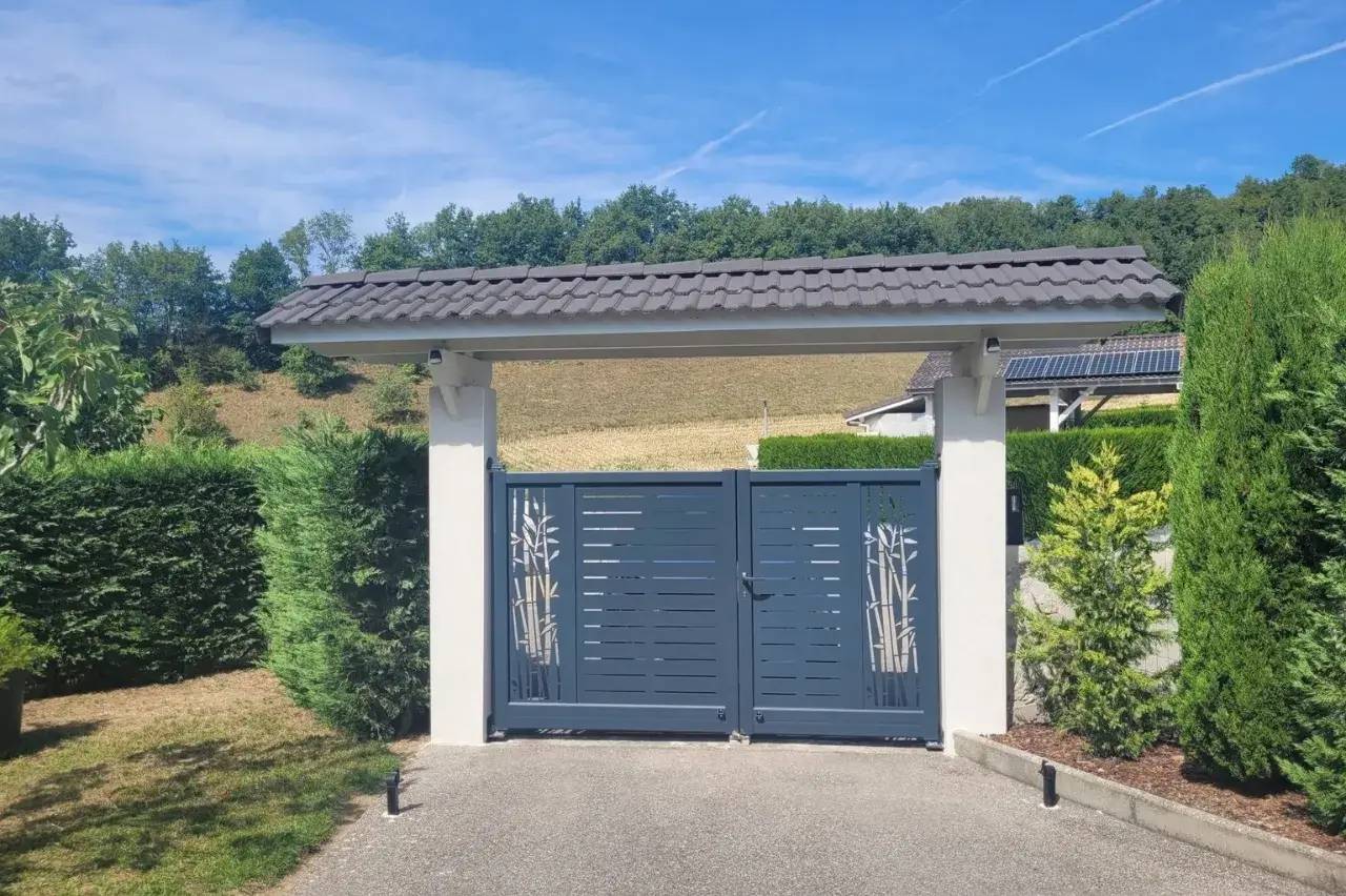 Portail moderne en métal gris orné de motifs de bambou, encadré par des piliers et un toit en tuiles, situé