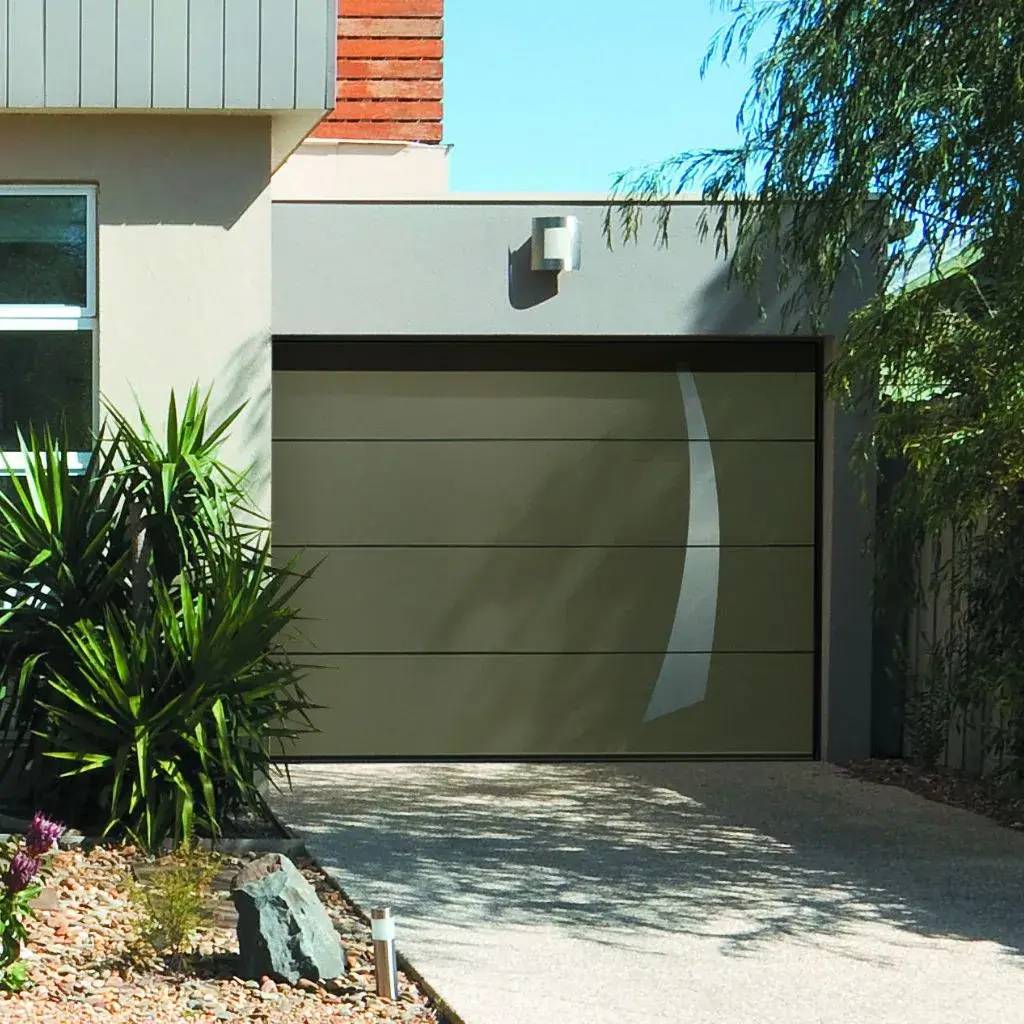 Une entrée de garage moderne avec une porte en métal beige, entourée de plantes et de pierres décoratives.