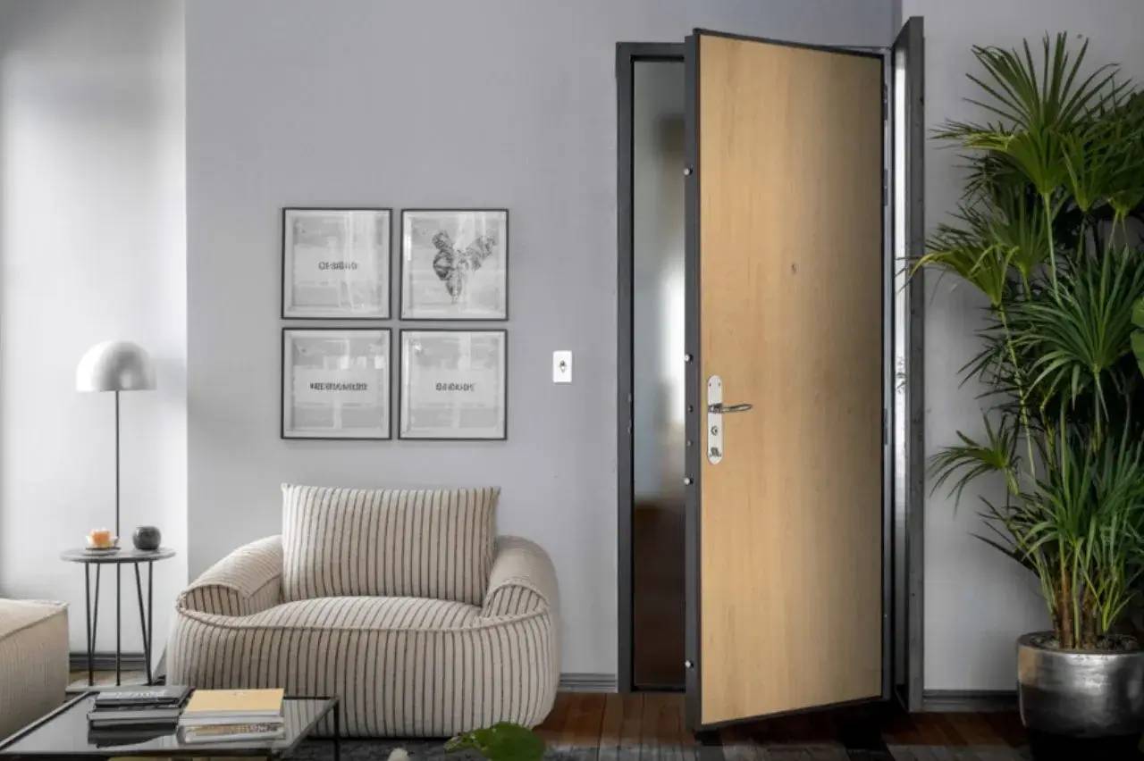 Un intérieur moderne et accueillant avec un canapé rayé, quatre cadres accrochés au mur, une porte en bois ouverte et une grande plante en