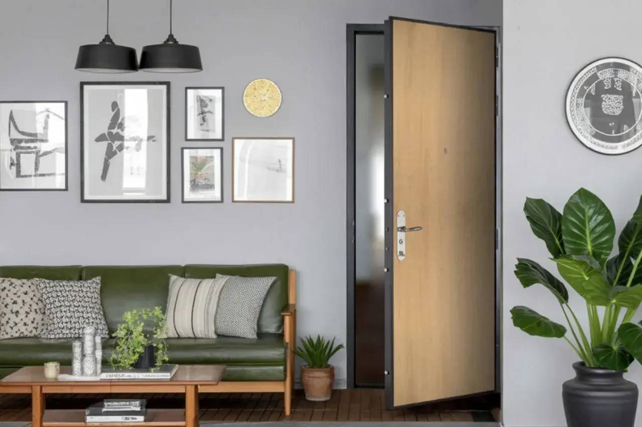 Un salon moderne avec un canapé vert, des coussins variés, une table basse en bois, des cadres muraux décoratifs, des plantes vert