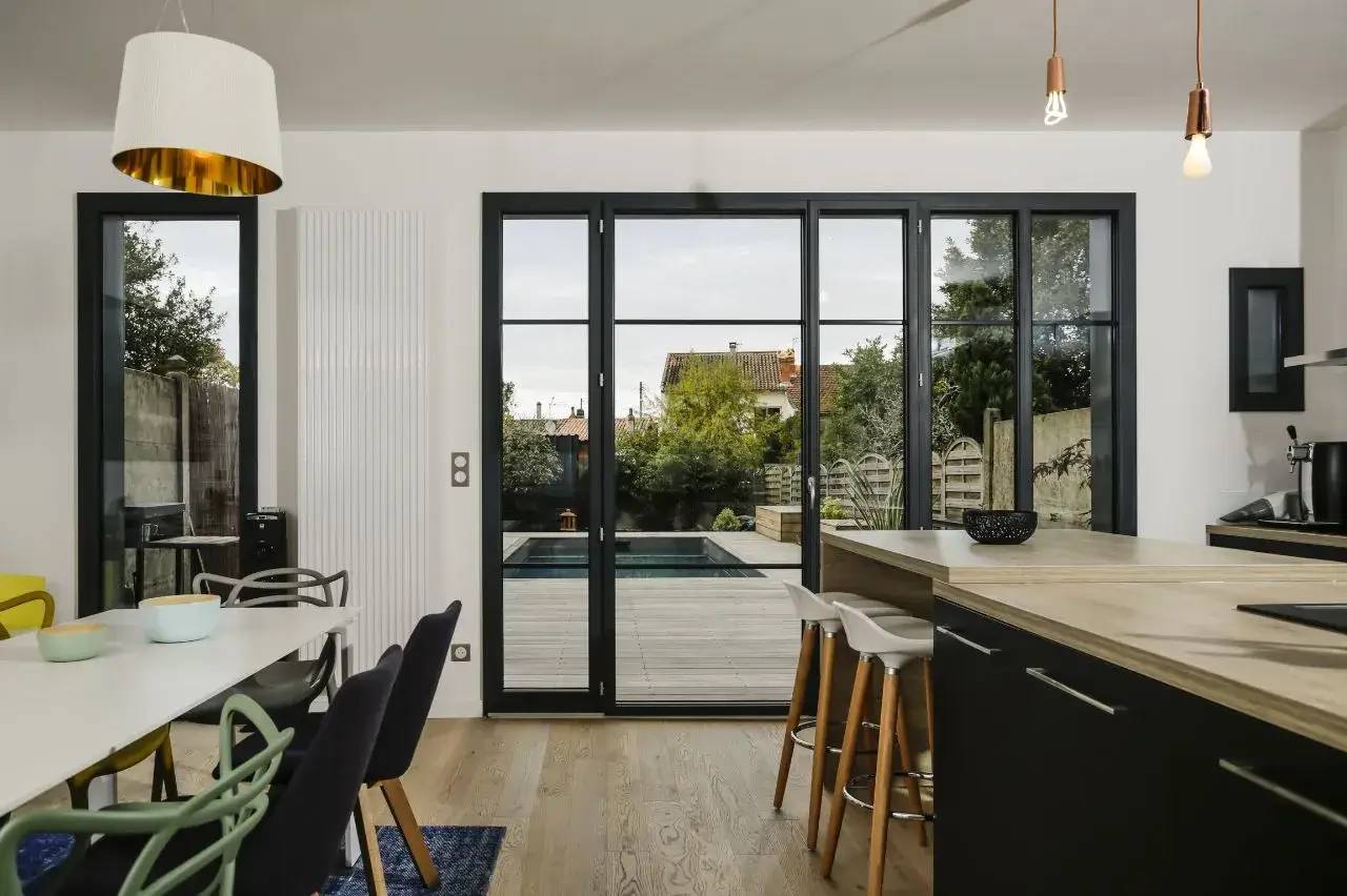 Une cuisine moderne et lumineuse ouverte sur une terrasse avec vue sur un jardin.