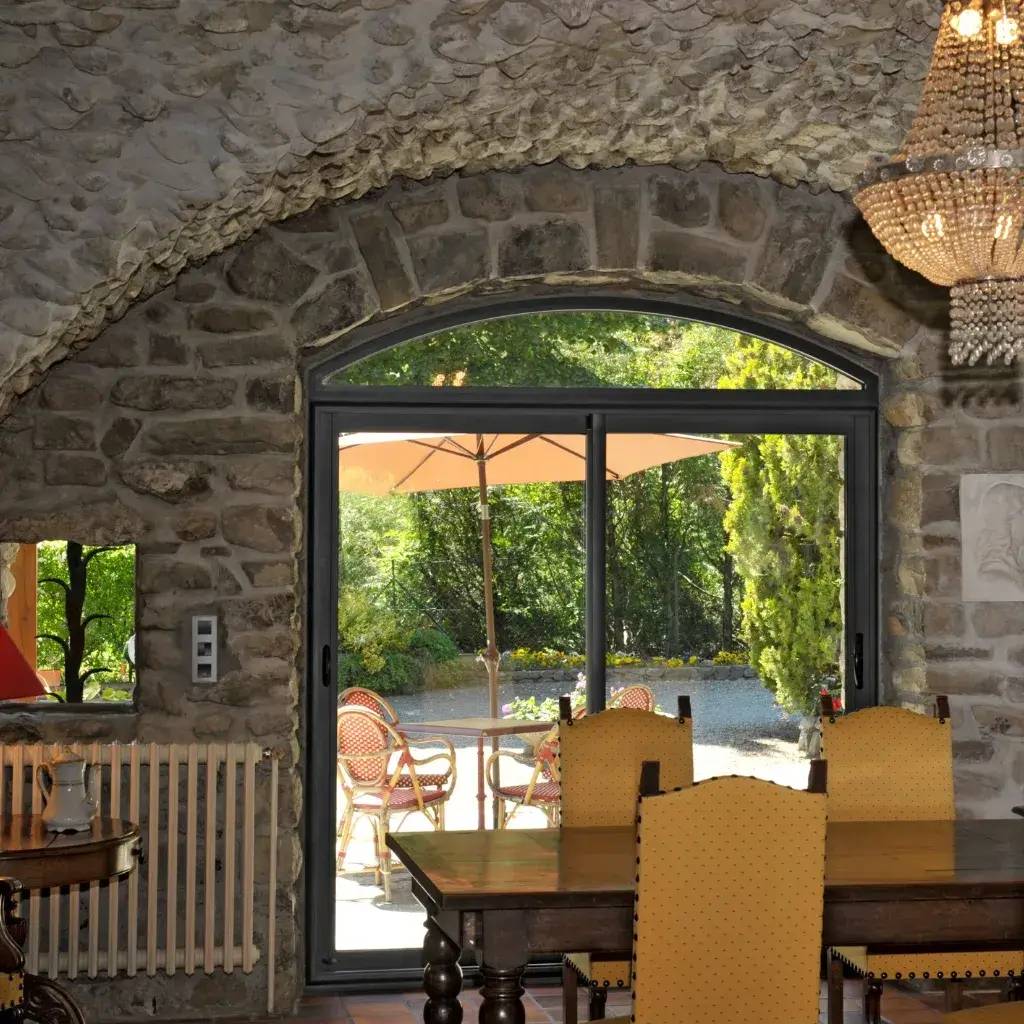 Un intérieur en pierre avec une grande porte vitrée donnant sur un jardin ensoleillé, équipé de meubles de patio orange.