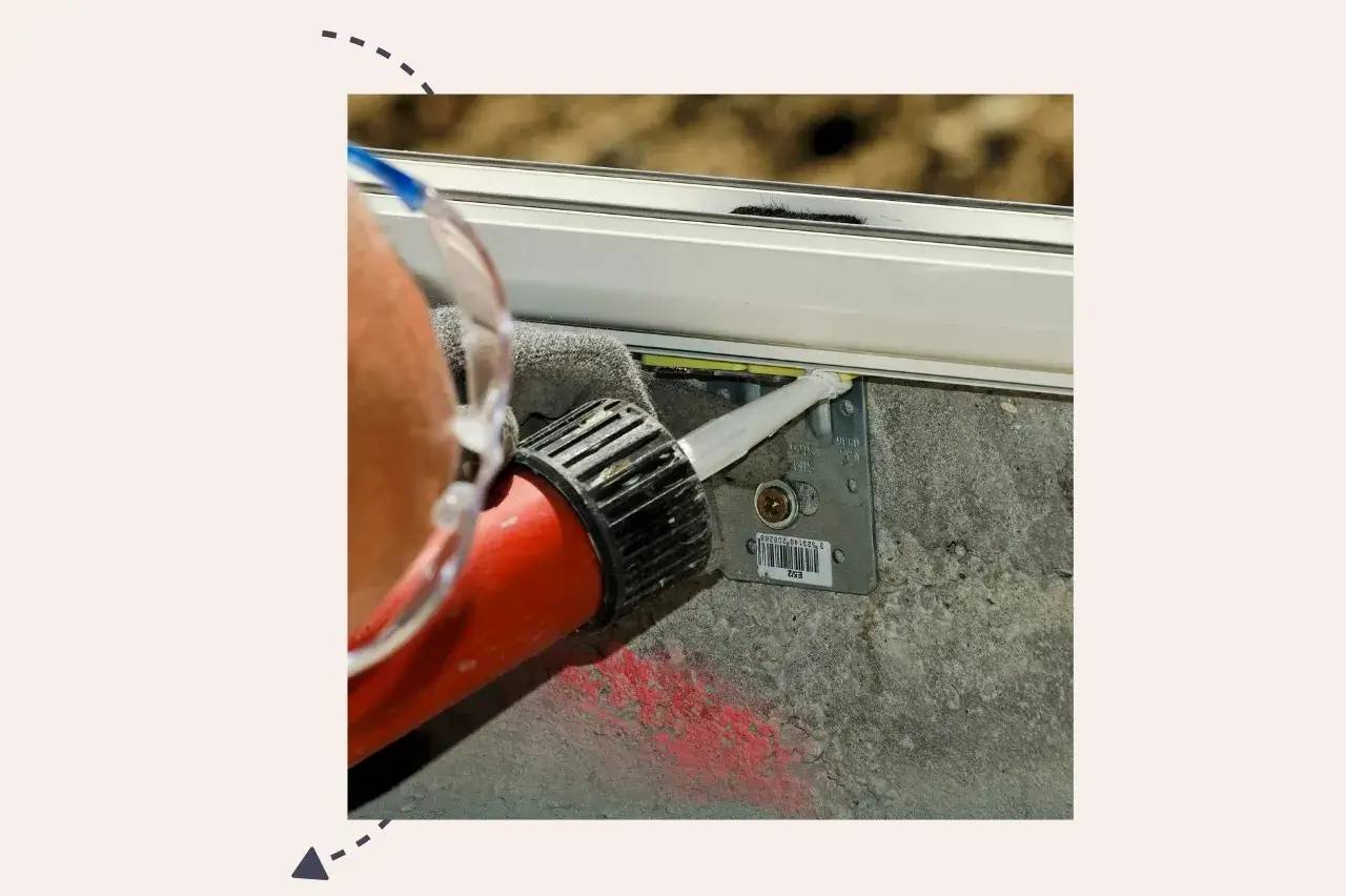 Un ouvrier applique un joint de silicone sur un cadre de fenêtre en cours d'installation.