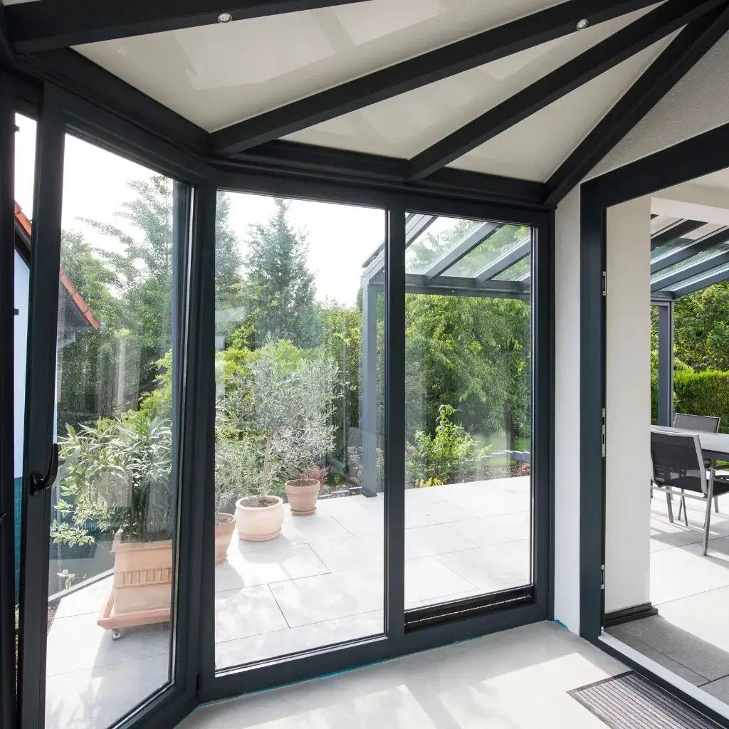 Cette image montre une véranda moderne avec des baies vitrées offrant une vue sur un jardin verdoyant.