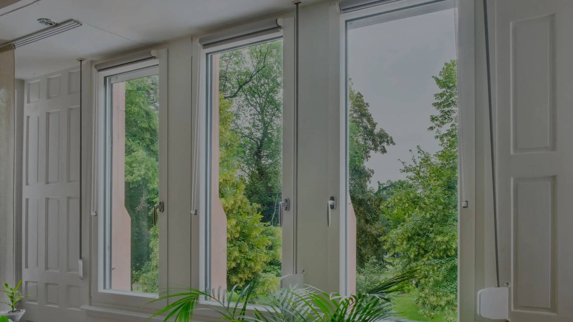 Vue intérieure lumineuse avec de grandes fenêtres donnant sur un jardin verdoyant.