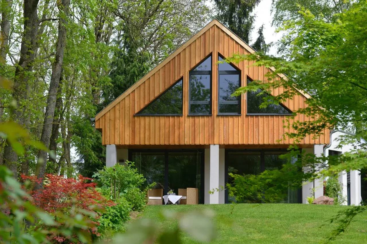 Une maison en bois au design moderne, entourée de verdure luxuriante et de jardins fleuris.