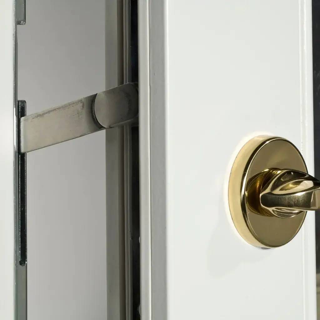 Gros plan sur un verrou de sécurité doré installé sur une porte métallique blanche.