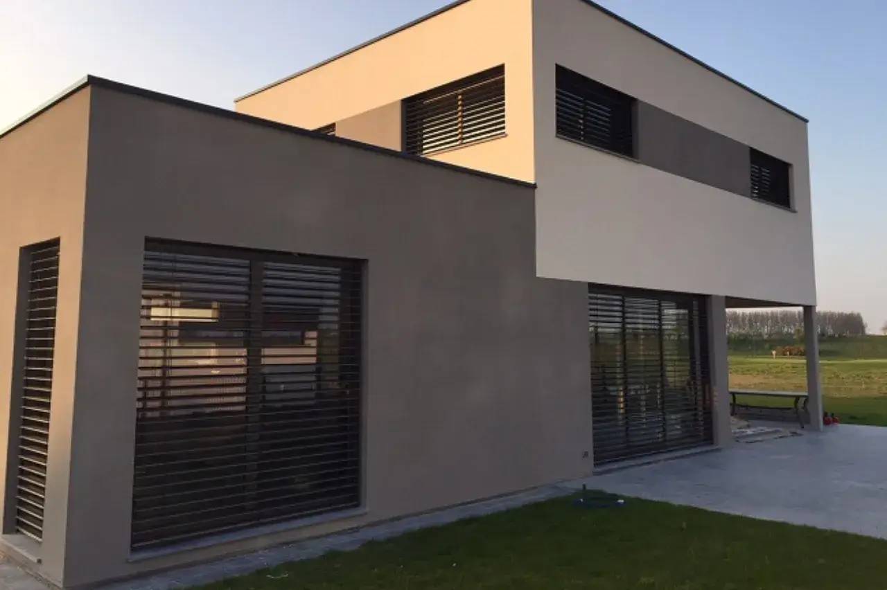 Maison contemporaine à deux étages avec façades en ton neutre et grandes fenêtres à stores.