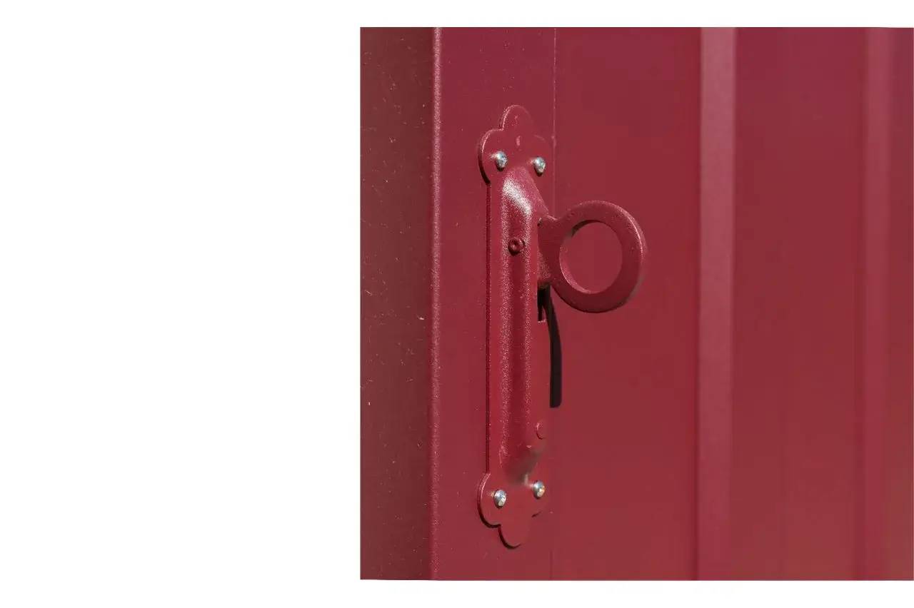 Gros plan sur une poignée rouge en métal fixée à une porte assortie.