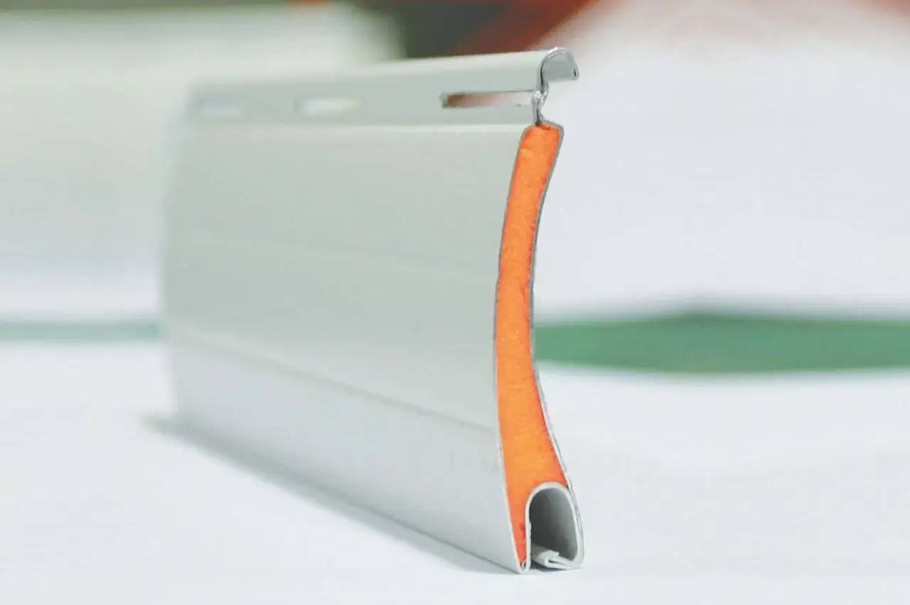 Une bande d'étanchéité orange et blanche est posée sur une surface blanche, mettant en valeur ses bords métalliques lisses et sa