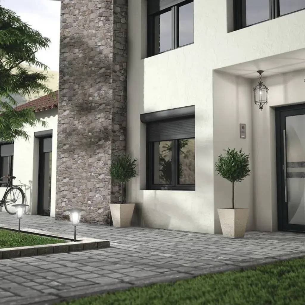 Façade moderne d'une maison avec un mur en pierre, des jardinières et une entrée élégante sous un éclairage extérieur.