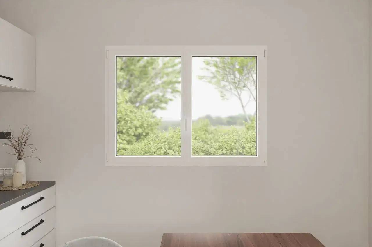 Une fenêtre intérieure blanche donne sur un paysage verdoyant, avec un plan de travail et des tiroirs à gauche.