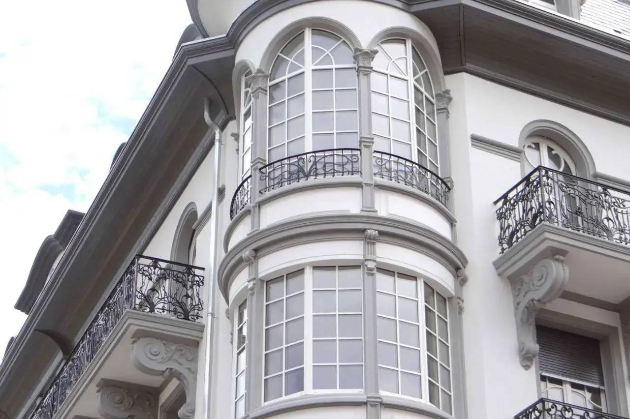Façade élégante d'un bâtiment ancien avec de grandes fenêtres cintrées et des balcons en fer forgé.