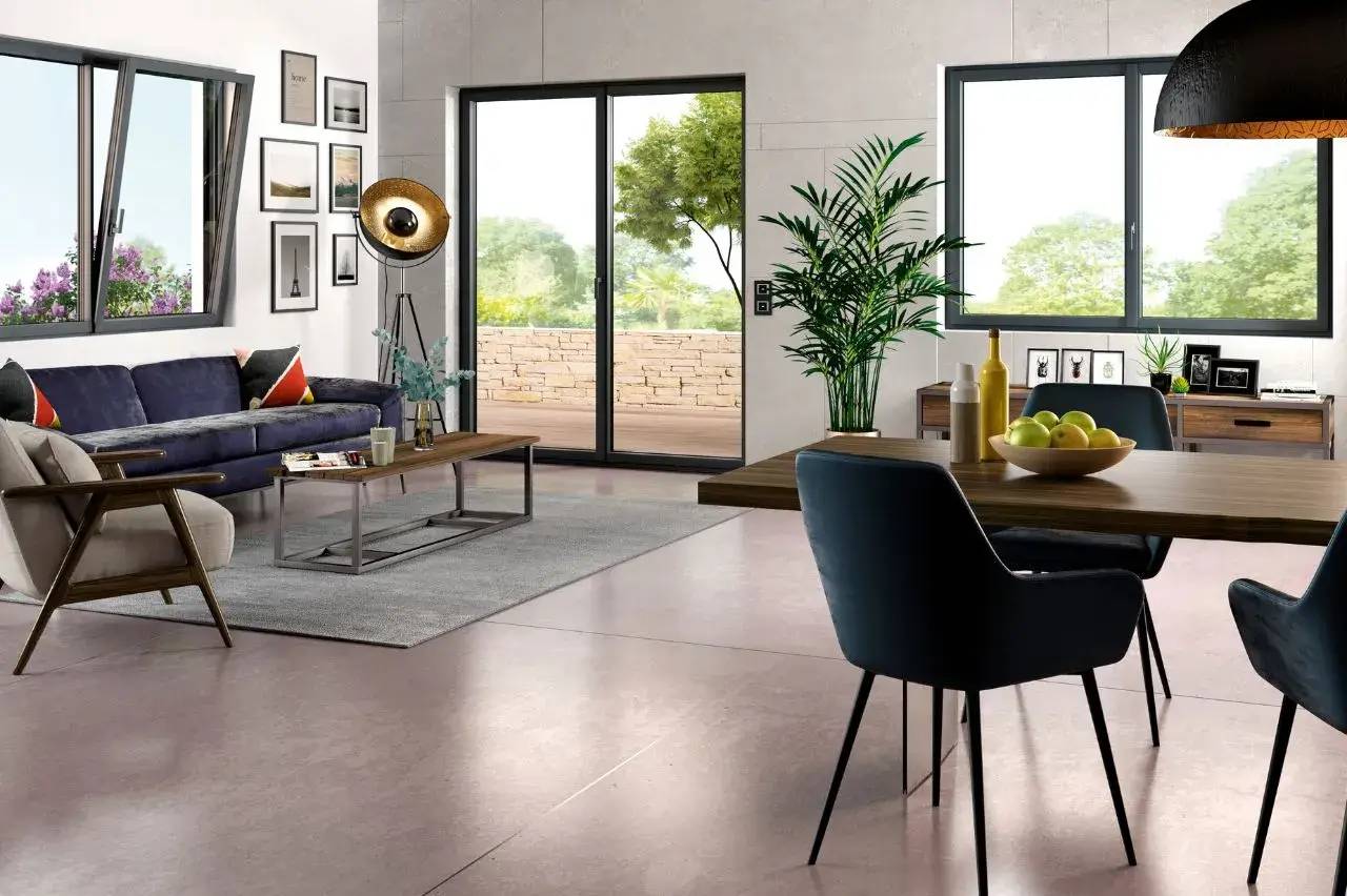 Un salon moderne et lumineux avec des grandes fenêtres, un canapé bleu, des fauteuils en bois, et une décoration végétale.