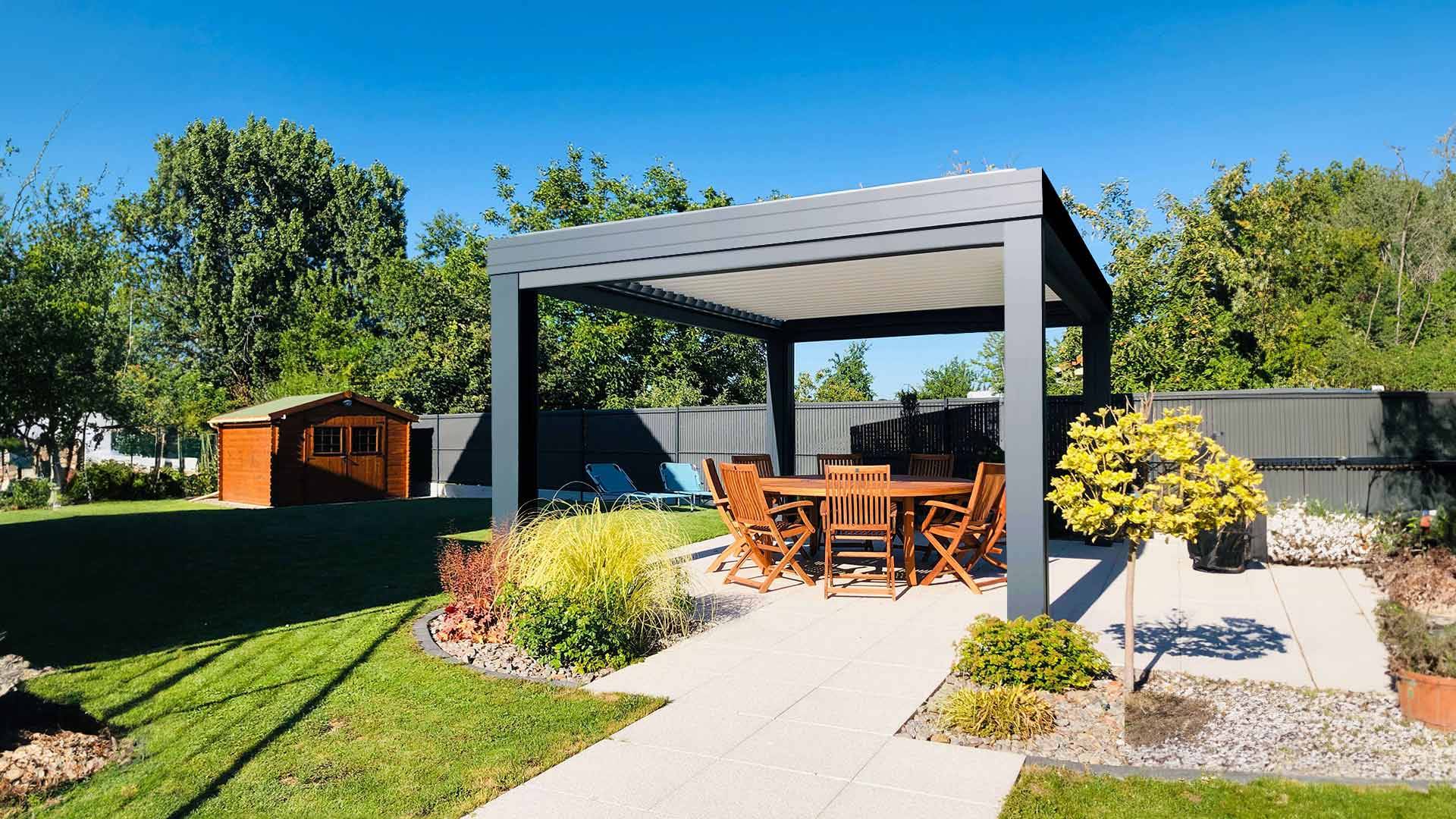 Salon à l'ombre sous pergola bioclimatique au milieu d'un jardin