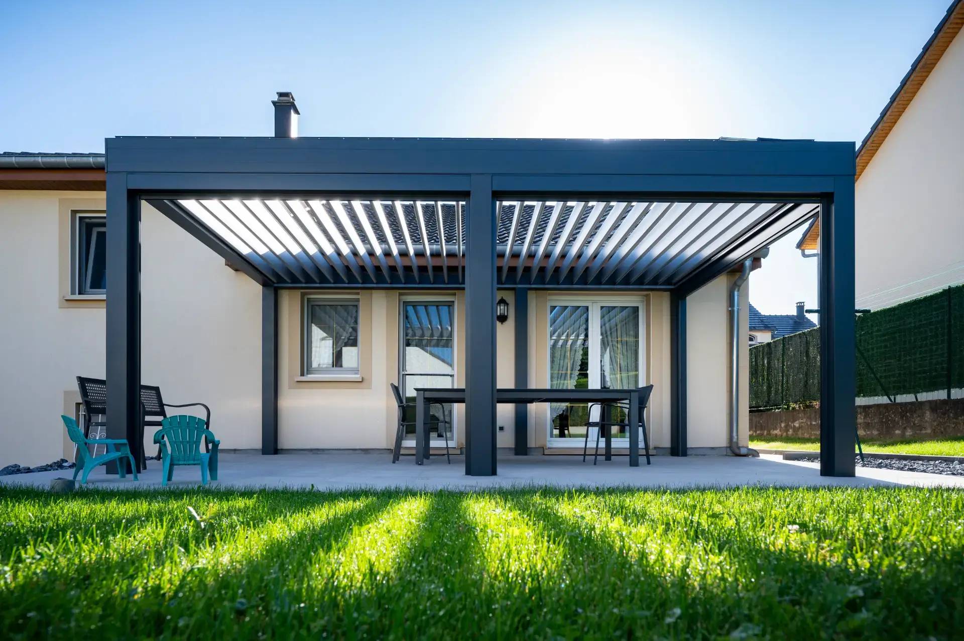 Pergola gris anthracite vue basse la lumière passe à travers les lamelles orientables