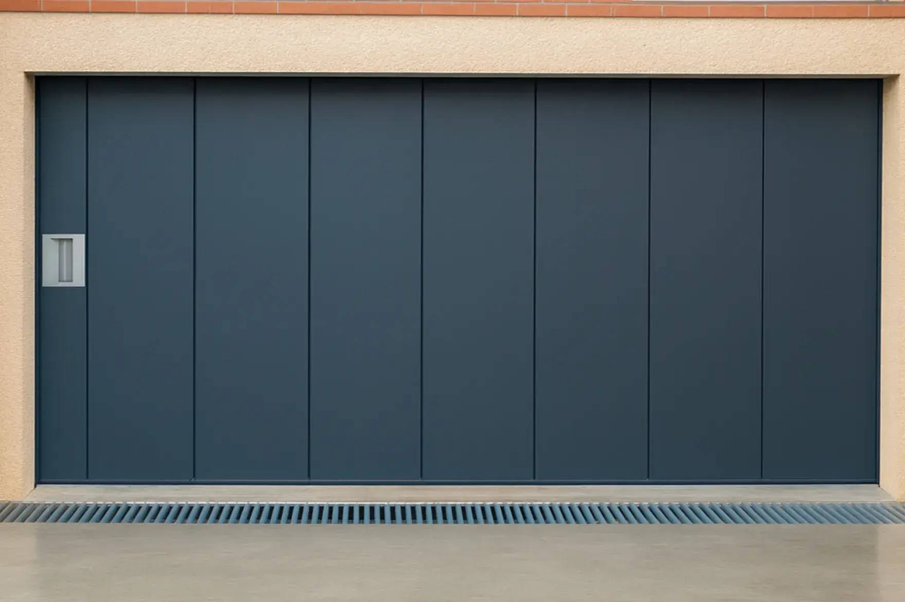 Porte de garage moderne et minimaliste de couleur gris anthracite, encadrée de murs beige.