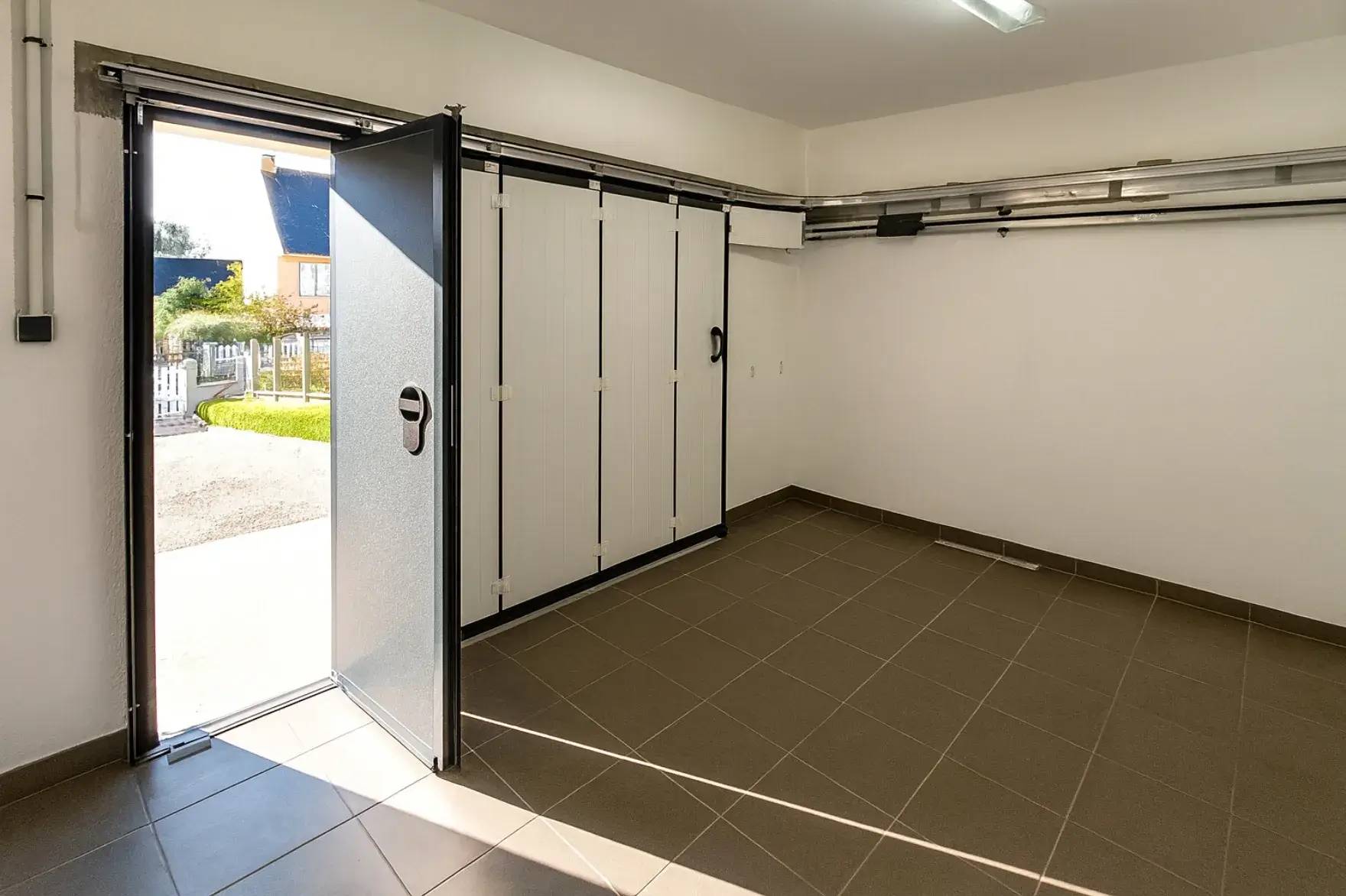 Garage spacieux et lumineux avec une grande porte ouverte sur l'extérieur.