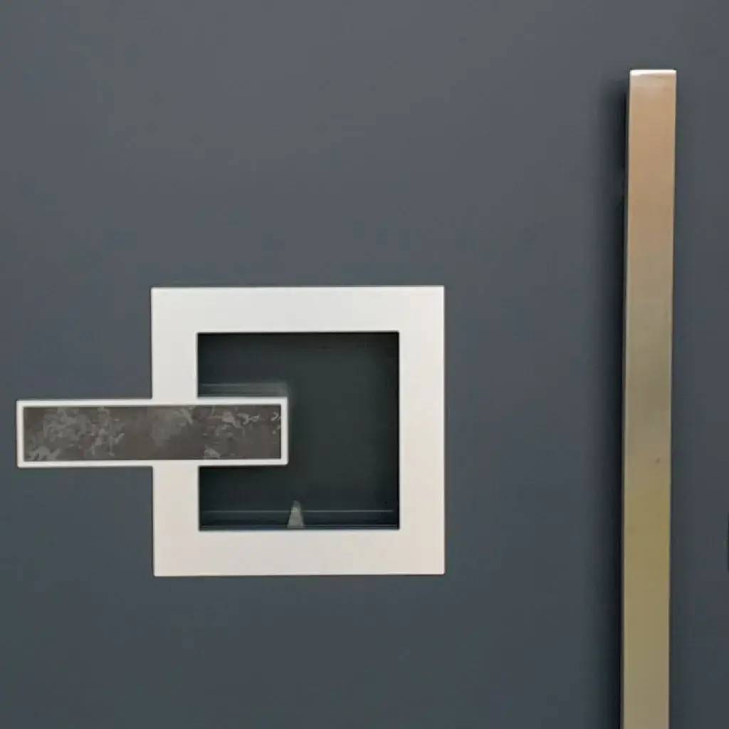 Image d'une porte moderne avec une poignée rectangulaire en métal contrastant sur un fond gris foncé.